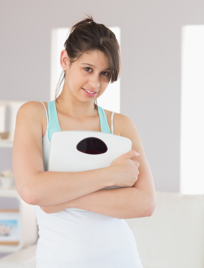 photodune-12541635-fit-brunette-smiling-at-camera-holding-scales-at-home-in-the-living-room-xl.jpg